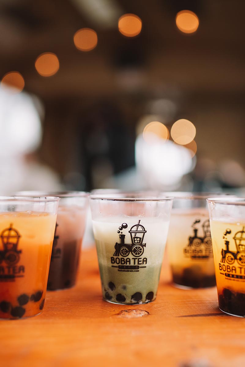 Black boba pearls decorate iced drinks on a wooden counter