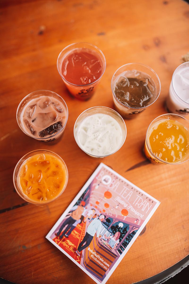 An array of iced boba drinks sit on a wooden counter