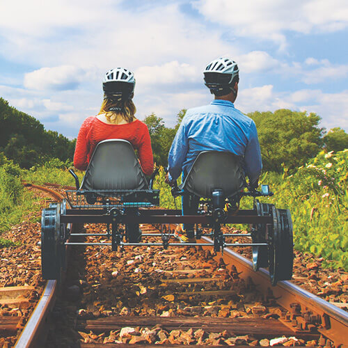 A woman and a man pedal a railbike down the track
