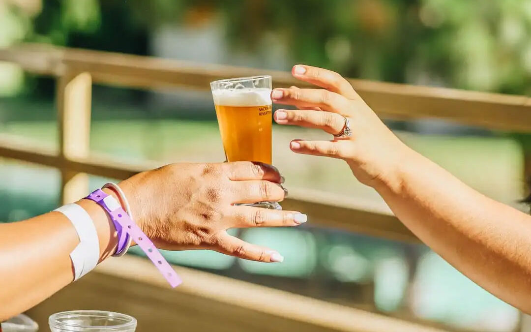 A bartender hands a glass of beer to a patron