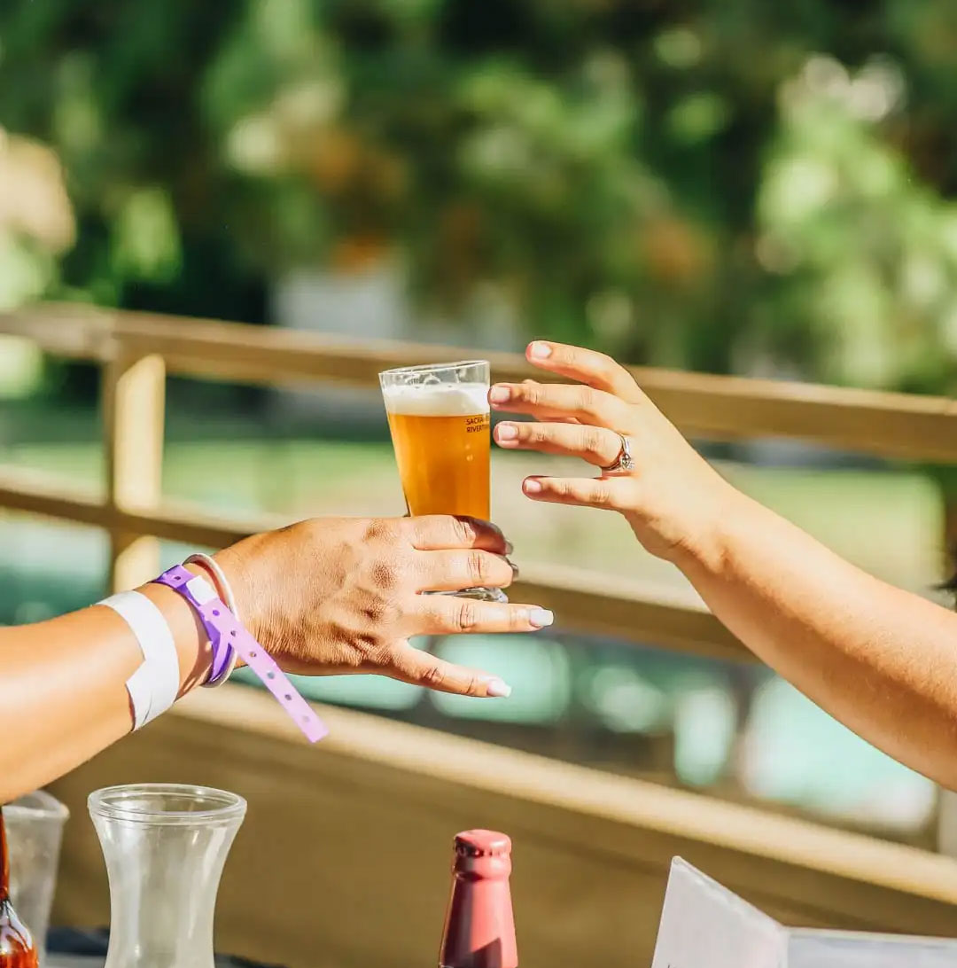 A bartender hands a glass of beer to a patron