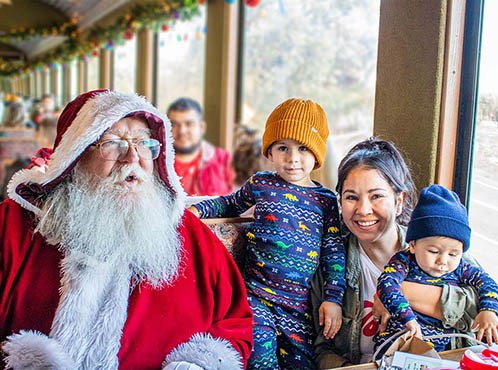 Santa with a family and kids in winter clothes on a festive train.