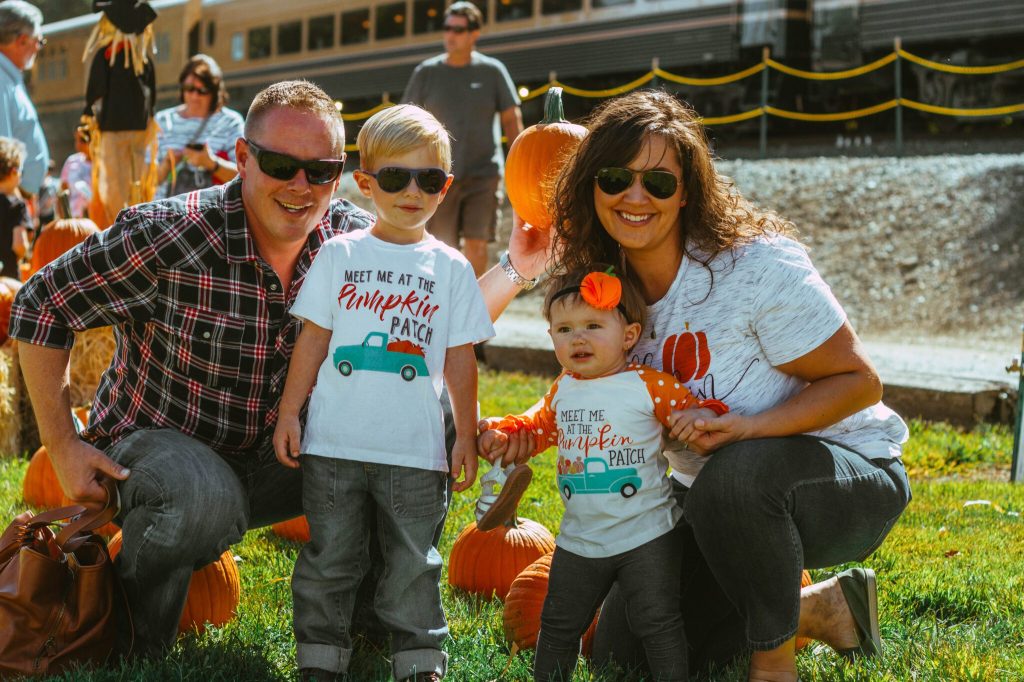 Family with two children at a pumpkin patch event.