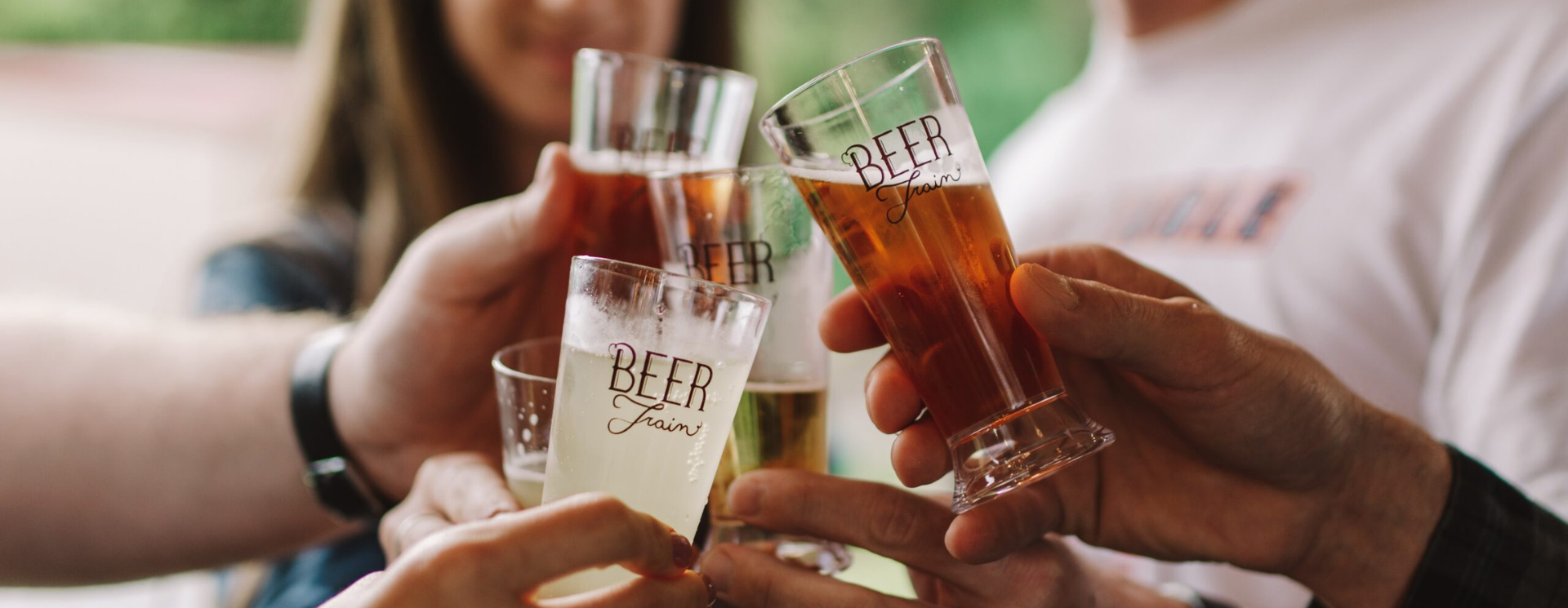 Group toasting with various beer glasses outdoors.