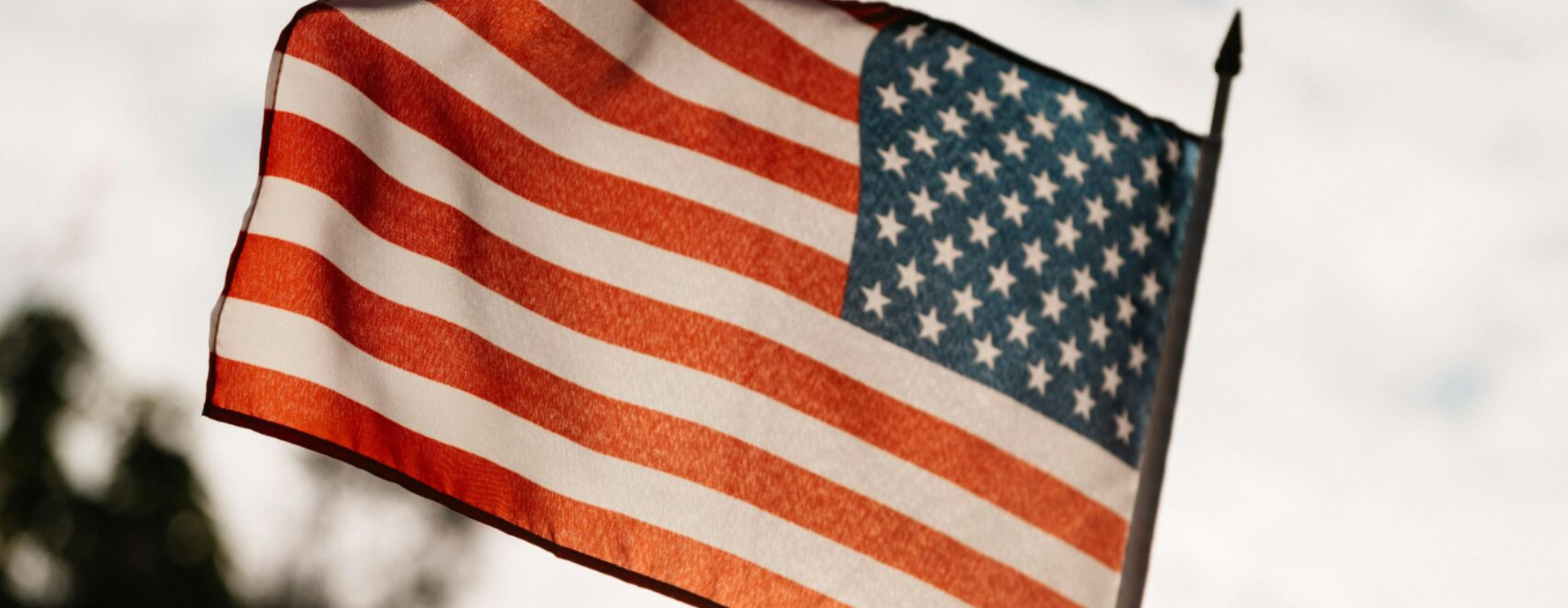 American flag waving in the wind against a cloudy sky.
