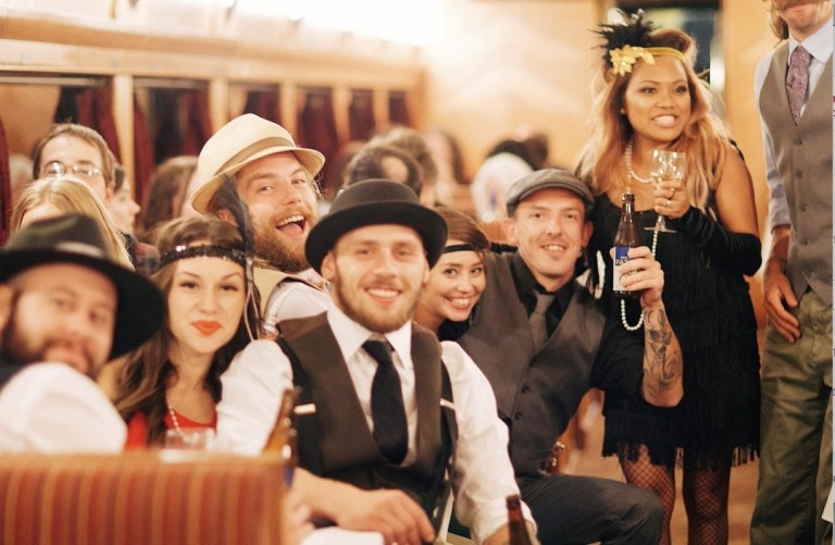Group of people smiling in 1920s-themed attire at a party.