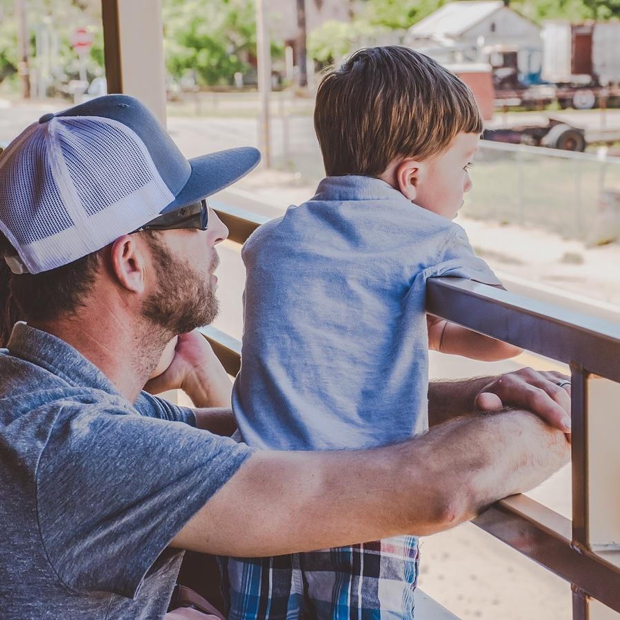 Man in cap with boy looking over railing.