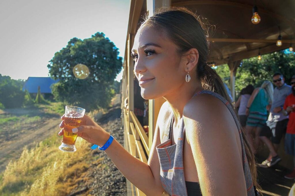 Woman enjoying a drink on a sunny outdoor train ride.