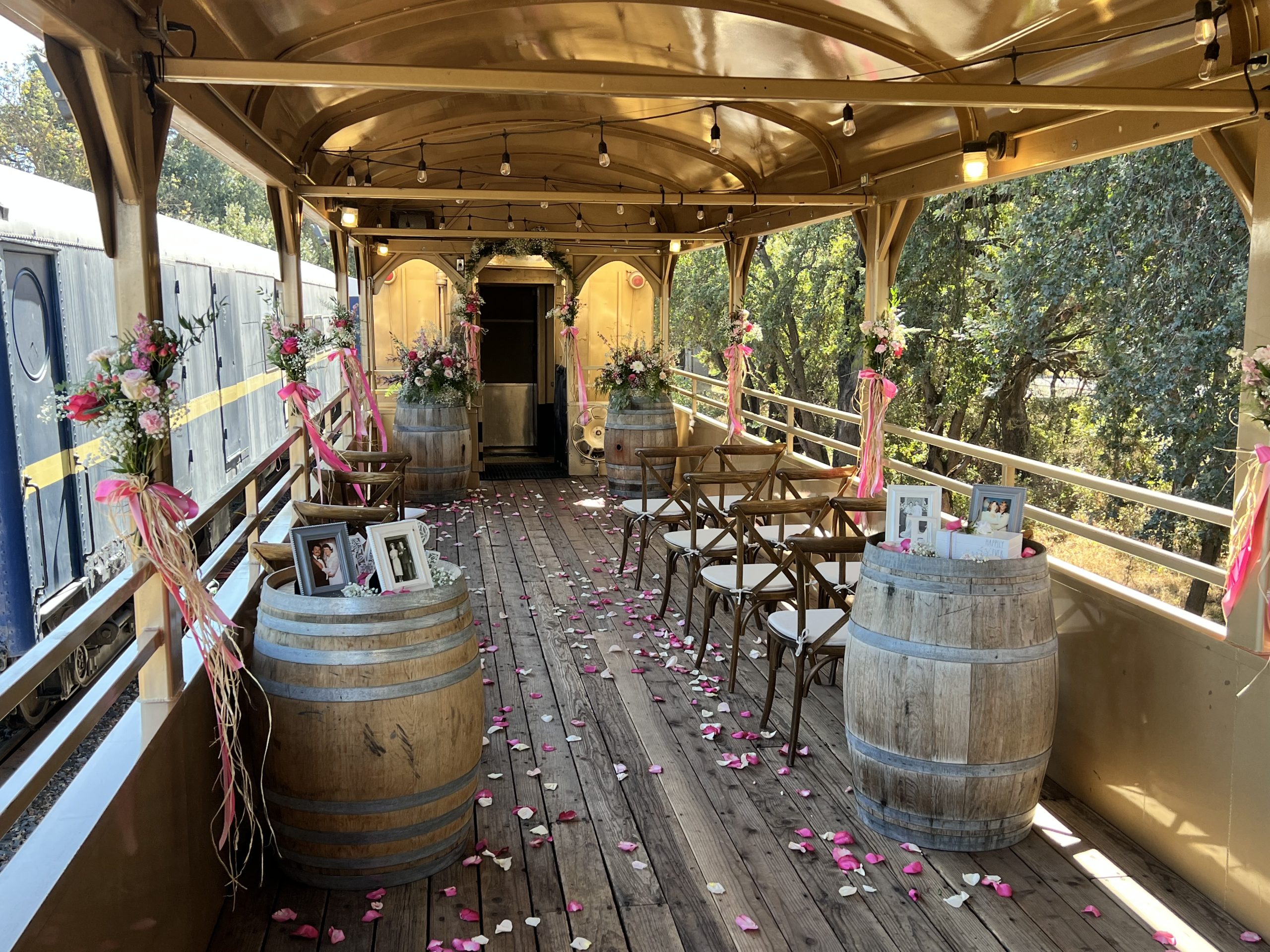 Train car with wooden barrels, chairs, flowers, and petals on the floor.
